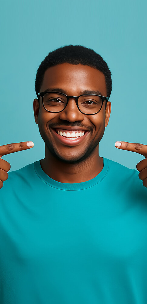Mann mit Brille in türkisfarbenem T-Shirt lächelt und zeigt mit beiden Händen auf sein Lächeln, Hintergrund türkis.