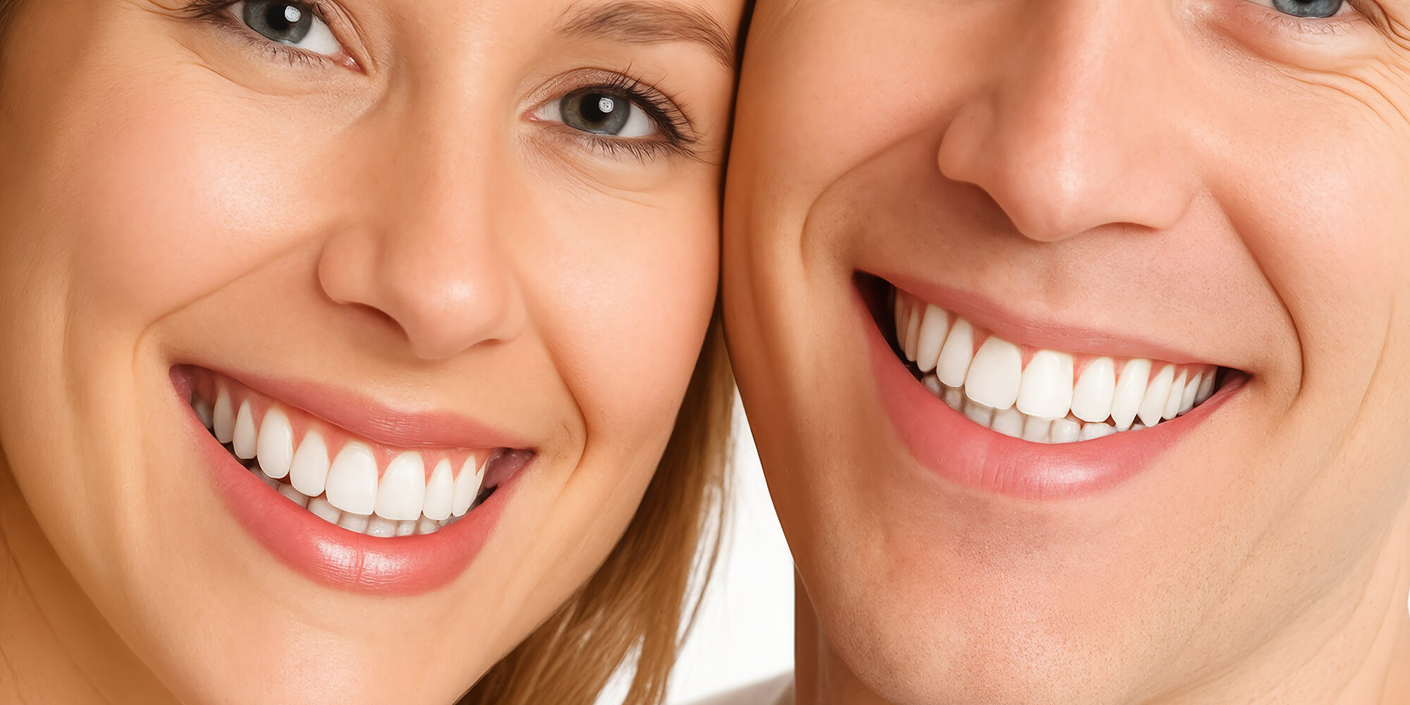 Ein Paar schaut in die Kamera und Lächelt, man sieht schöne Zähne