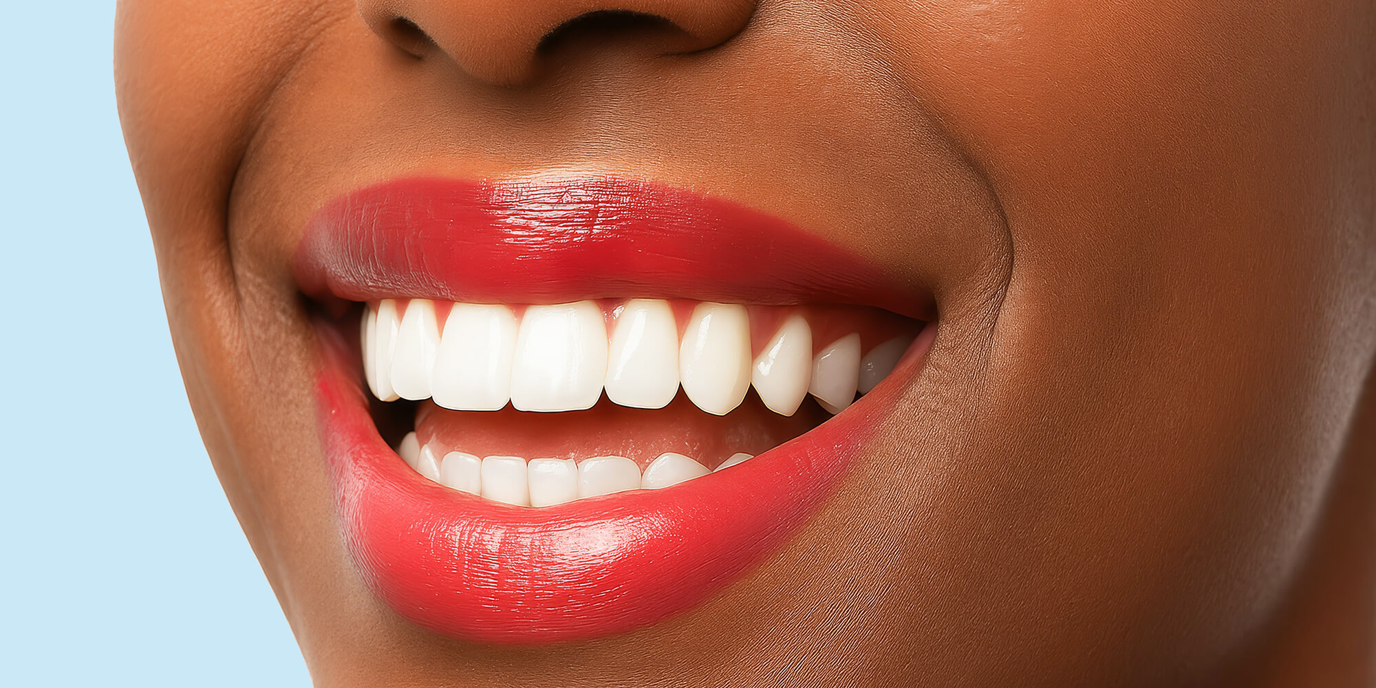 Nahaufnahme eines strahlenden Lächelns mit roten Lippen – Symbol für ästhetische Zahnbehandlung und gepflegte Zähne.