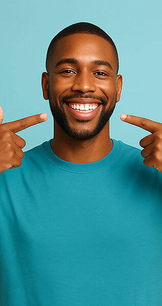 Lächelnder Mann zeigt mit beiden Zeigefingern auf sein Gebiss.